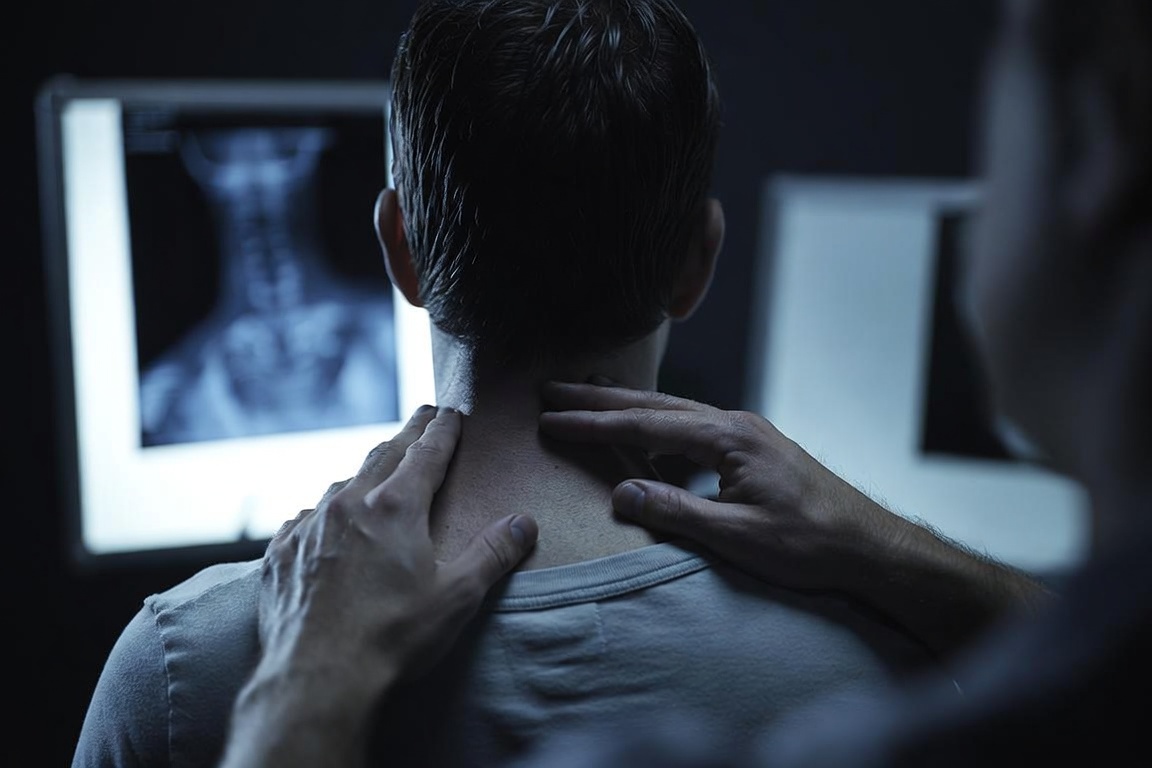 Doctor examining a car accident patient's neck and back to evaluate and document injuries